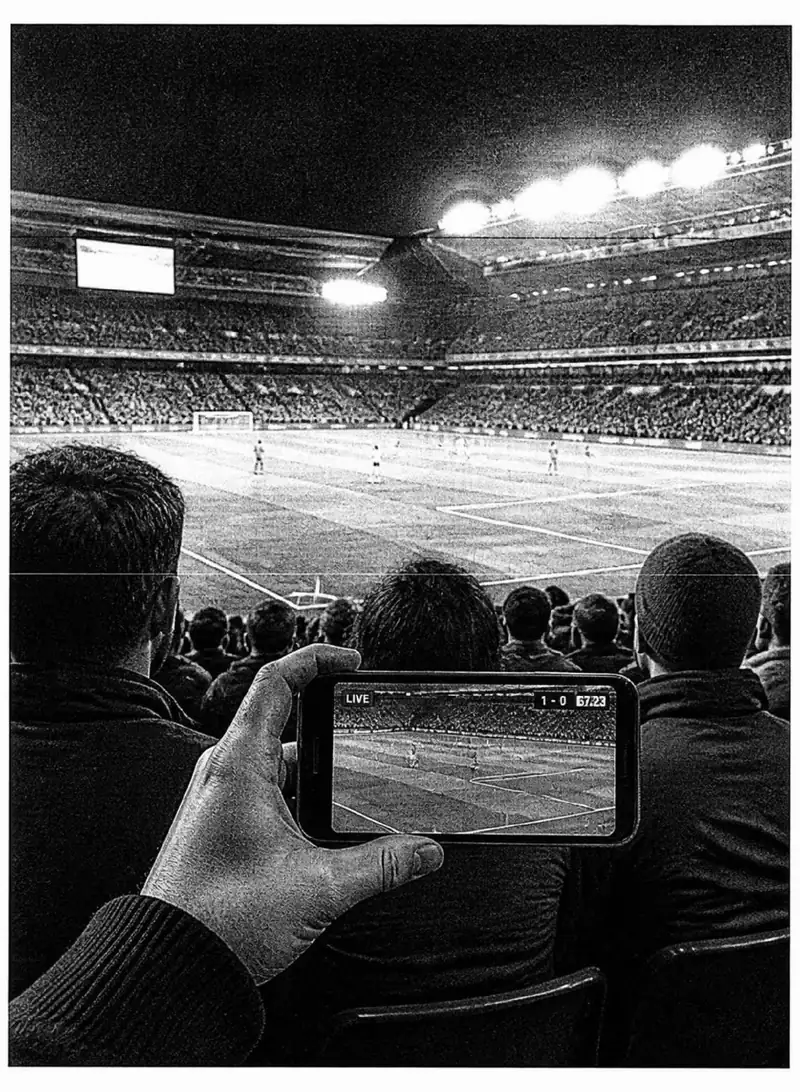 A phone showing a football match in a stadium